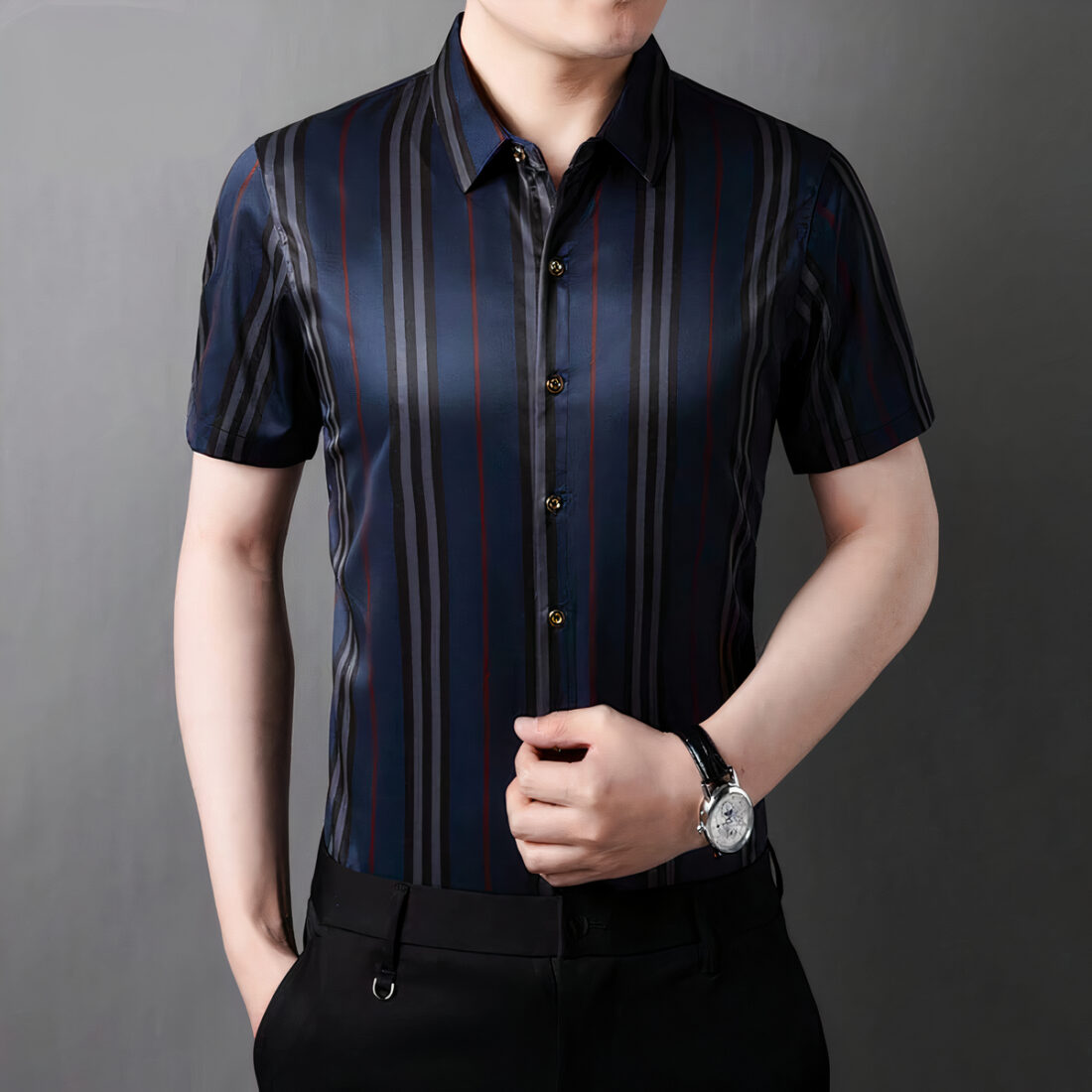 Homme portant une chemise à rayures sur fond gris.