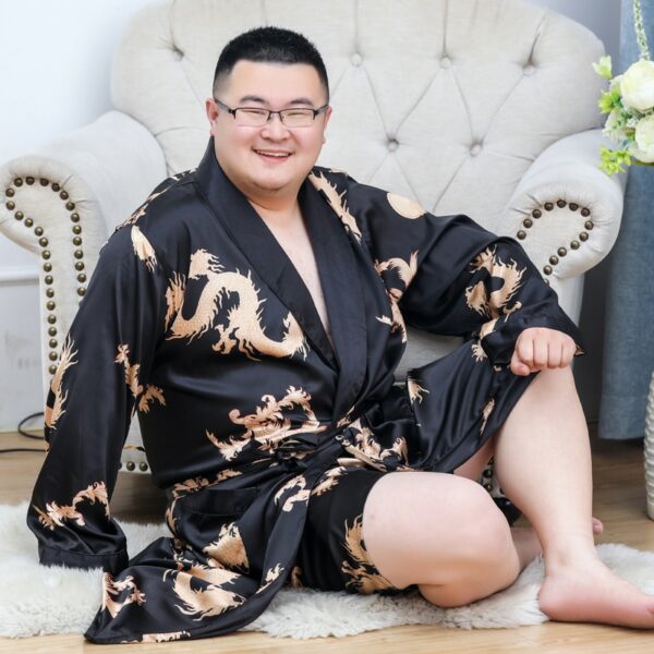 Homme assis par terre devant un fauteuil et portant un kimono noir.