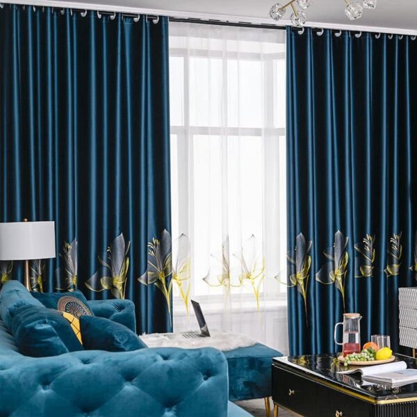 Rideaux bleus sur une fenètre avec un canapé bleu devant, une lampe blanche et une table basse devant le canapé.