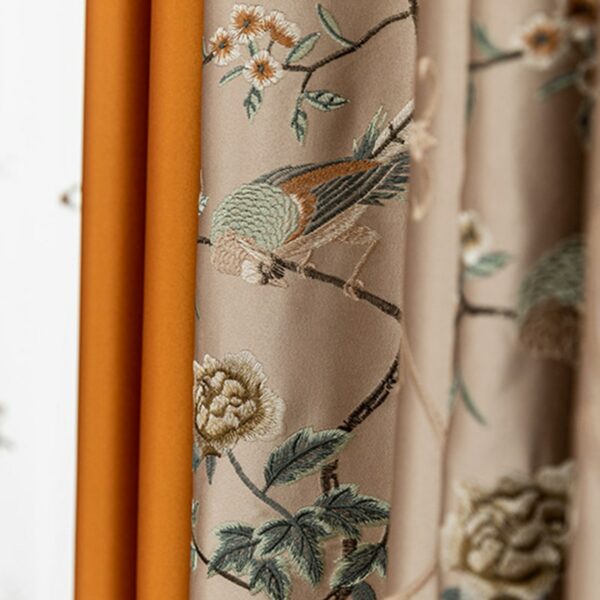 Rideau beige avec des motifs de fleurs et d'oiseaux avec un rideau orange derrière