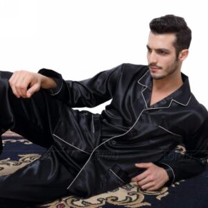 Homme en position presque allongé portant un pyjama en satin noir