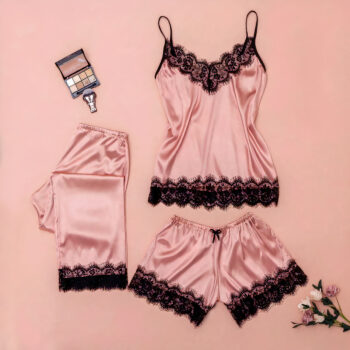 Pyjama 3 pièces rose composé d'un débardeur, un short et un pantalon en satin avec de la dentelle. Les trois vêtements sont posés à plat sur un fond rose avec une palette de maquillage à côté.