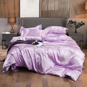 Lit avec des draps violets en satin avec un plaid marron par dessus. Moquette beige au sol et vas avec des fleurs posé à côté du lit.