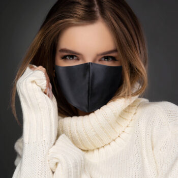 Masque noir en satin sur jeune femme à col roulé beige et cheveux chatains