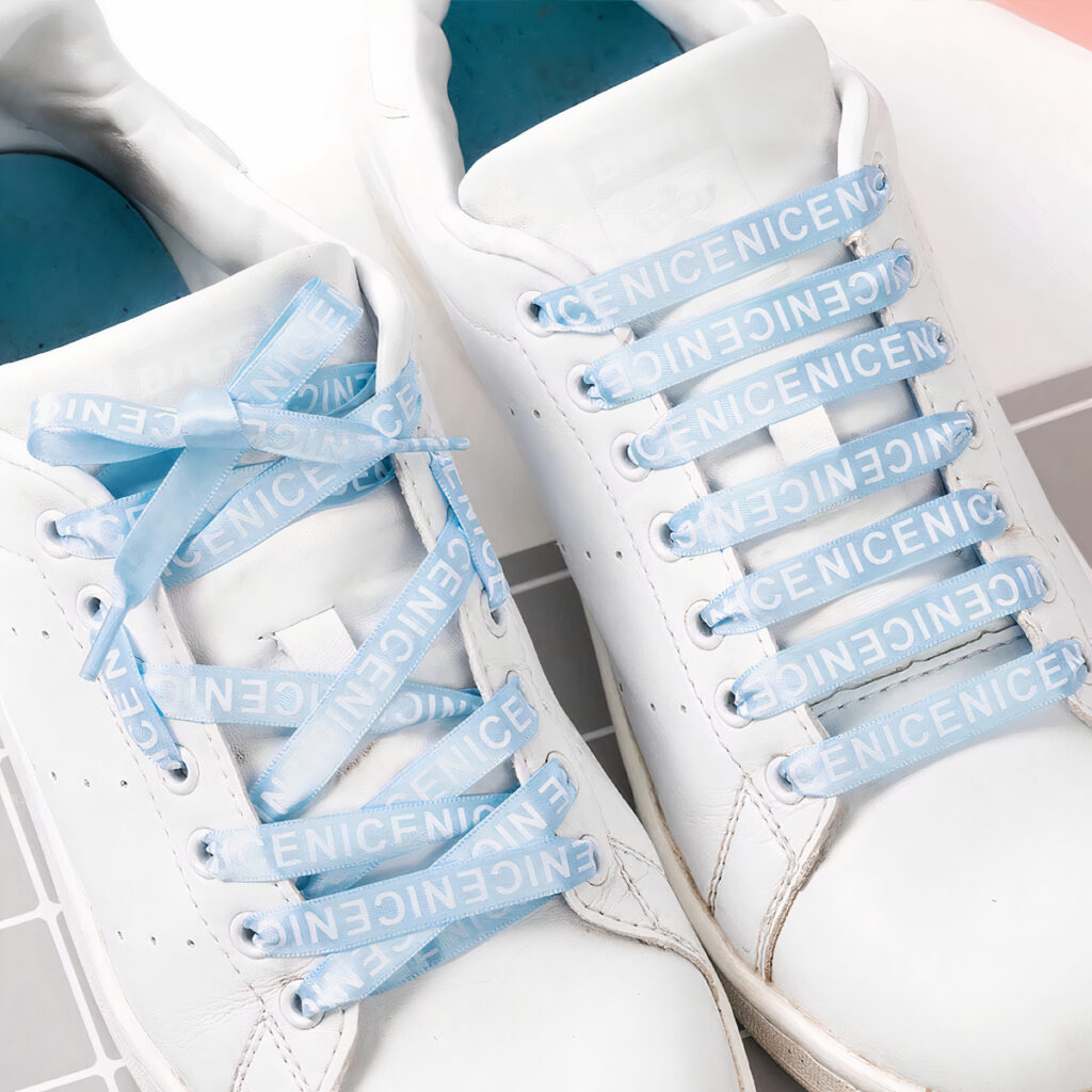 Chaussures blanches avec lacets bleus clair imprimés lettres blanches.