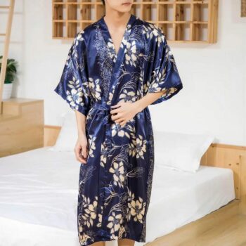 Homme debout devant un lit aux draps blancs portant un kimono bleu aux motifs fleurs