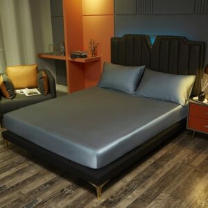 Très belle chambre masculine grise et orange avec un fauteuil club. Le lit est un lit double paré d'un drap housse en satin de soie