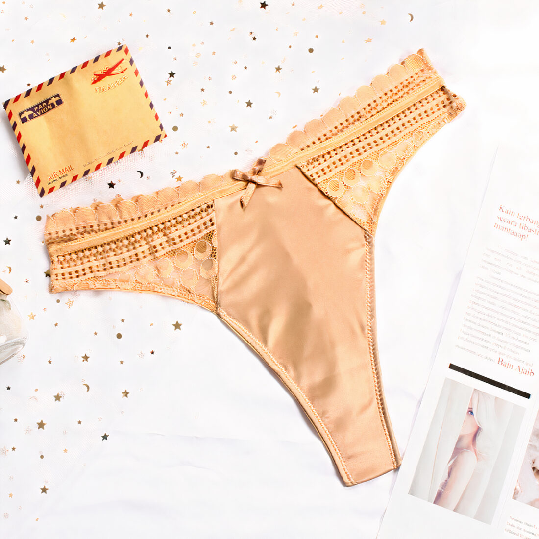 String beige en satin avec de la dentelle sur un fond blanc.