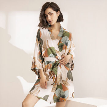 Femme portant un peignoir en satin beige imprimé de grandes feuilles dans des tons automnal