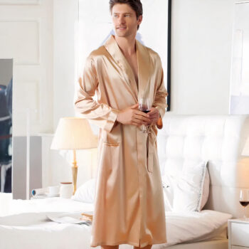 Homme debout dans une chambre portant une robe de chambre en satin beige
