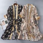 Deux robes de chambres en satin imprimés de plumes, une noire et une beige.