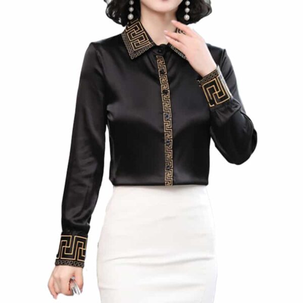 Femme portant une chemise en satin noir élégante avec des motifs géométriques sur la boutonnèere, le col et les manches avec une jupe blanche