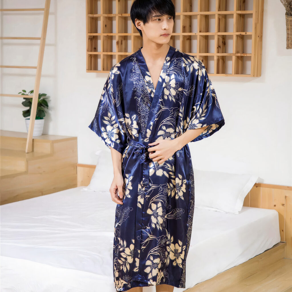 Homme portant un long kimono homme bleu à fleurs. En fond, on voit des escaliers.