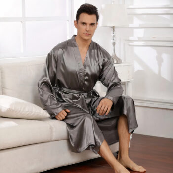 Homme assis sur un canapé beige portant un peignoir gris en satin.