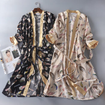 Deux robes de chambres, une noire à gauche, une beige à droite avec des motifs de plumes sur les 2, sur cintres, un magazine à gauche.