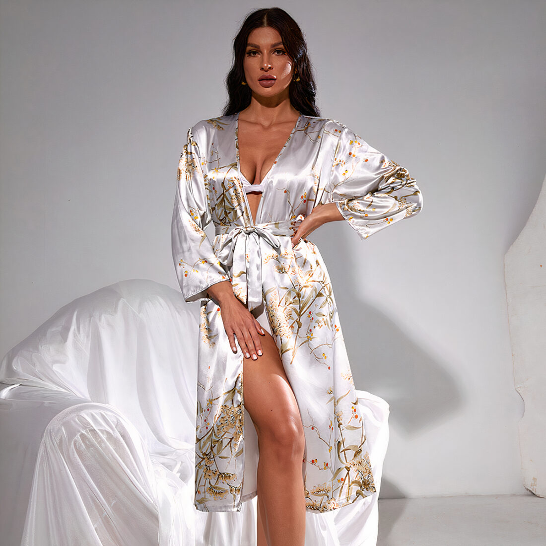 femme portant un peignoir en satin gris imprimé. Elle se tient devant un fauteuil blanc devant un mur blanc.