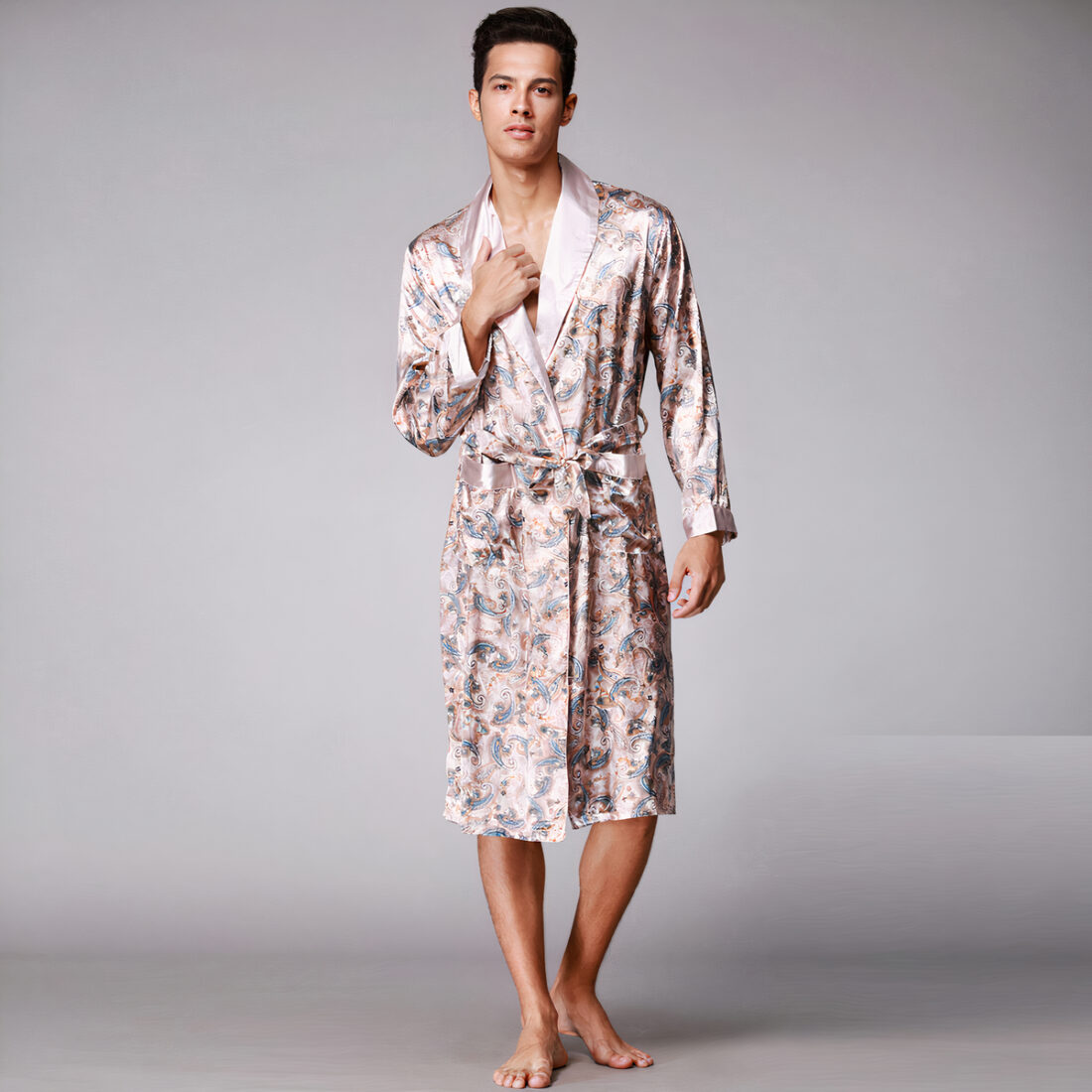 Homme portant une robe de chambre beige à motifs sur fond gris.