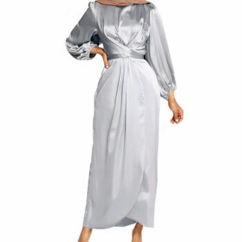 femme portant une robe longue à manche longue en satin gris. Sa main droite posée sur sa taille.