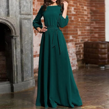 Une femme debout à côté d'une cheminée portant une robe de soirée à, manche longue verte