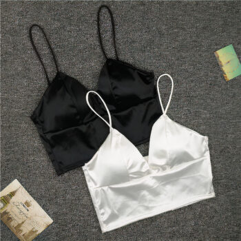 2 soutiens gorge large, avec bonnets en triangle et fines bretelles, un noir et un blanc dessus. Ils sont posés sur une moquette grise, 2 images à gauche et à droite.