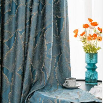Rideau bleu avec des motifs dorés posé sur une table basse avec un vase et des fleurs posé sur la table ainsi qu'une tasse de café posé sur le rideau
