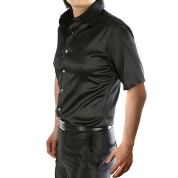 Homme debout portant une chemise noire à manches courtes avec un pantalon noir, de profil , les bras le long du corps.