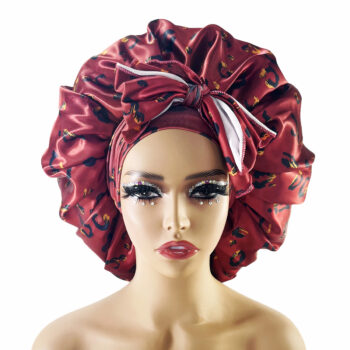 Tête à coiffer de face maquillée portant un bonnet en satin avec nœud sur le devant. Il est de couleur bordeaux avec des motifs léopard noirs.